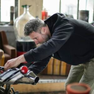 Professional adult bearded mechanic fixing motorcycle in workshop