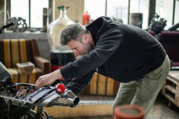 Professional adult bearded mechanic fixing motorcycle in workshop